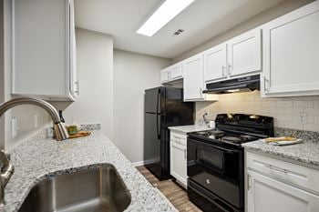 A kitchen with white cabinets and black appliances